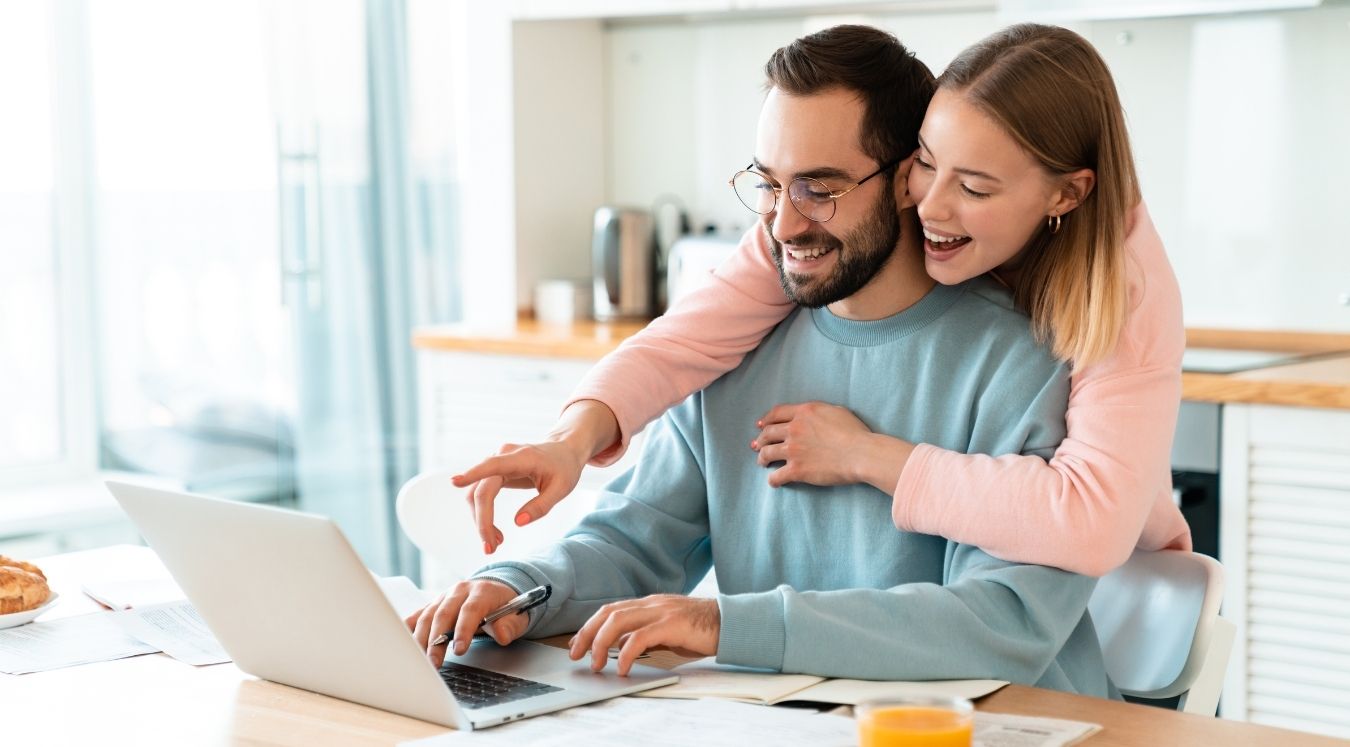 Une femme aide son conjoint devant un ordinateur à comprendre son bilan comptable