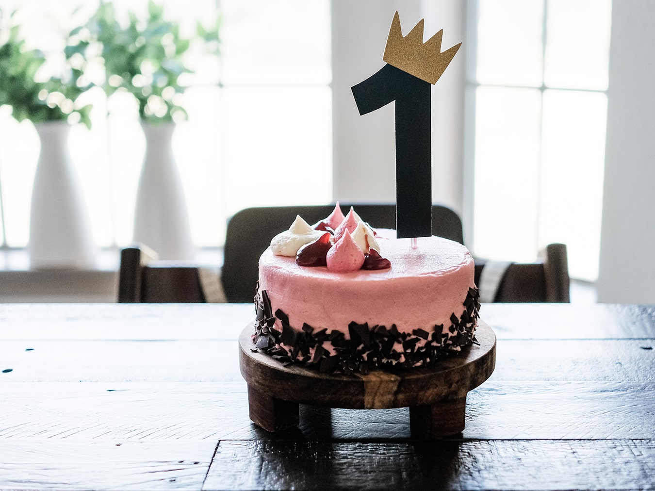 Gâteau d'anniversaire rose avec une table en bois et un chiffre 1 couronné dessus