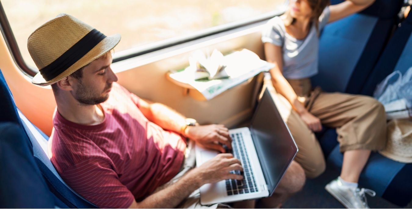 un freelance digital nomad en train de créer son compte en ligne à l'étranger dans le train
