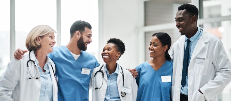 Equipe médicale souriante de 5 personnes multi ethniques se regardant dans les yeux
