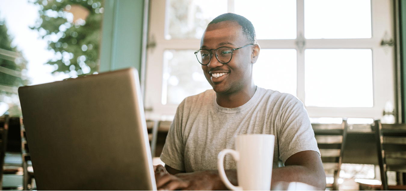 homme qui travaille sur ordinateur en souriant sur un logiciel de comptabilité en ligne